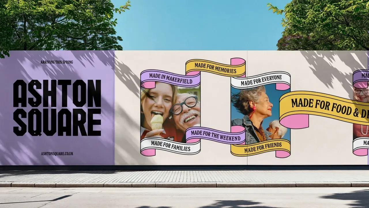 Palissade de chantier d'Ashton Square : typographie noire massive sur fond lilas et rubans roses et jaunes portant les mentions Made in Makerfield, Made for Memories, Made for Everyone
