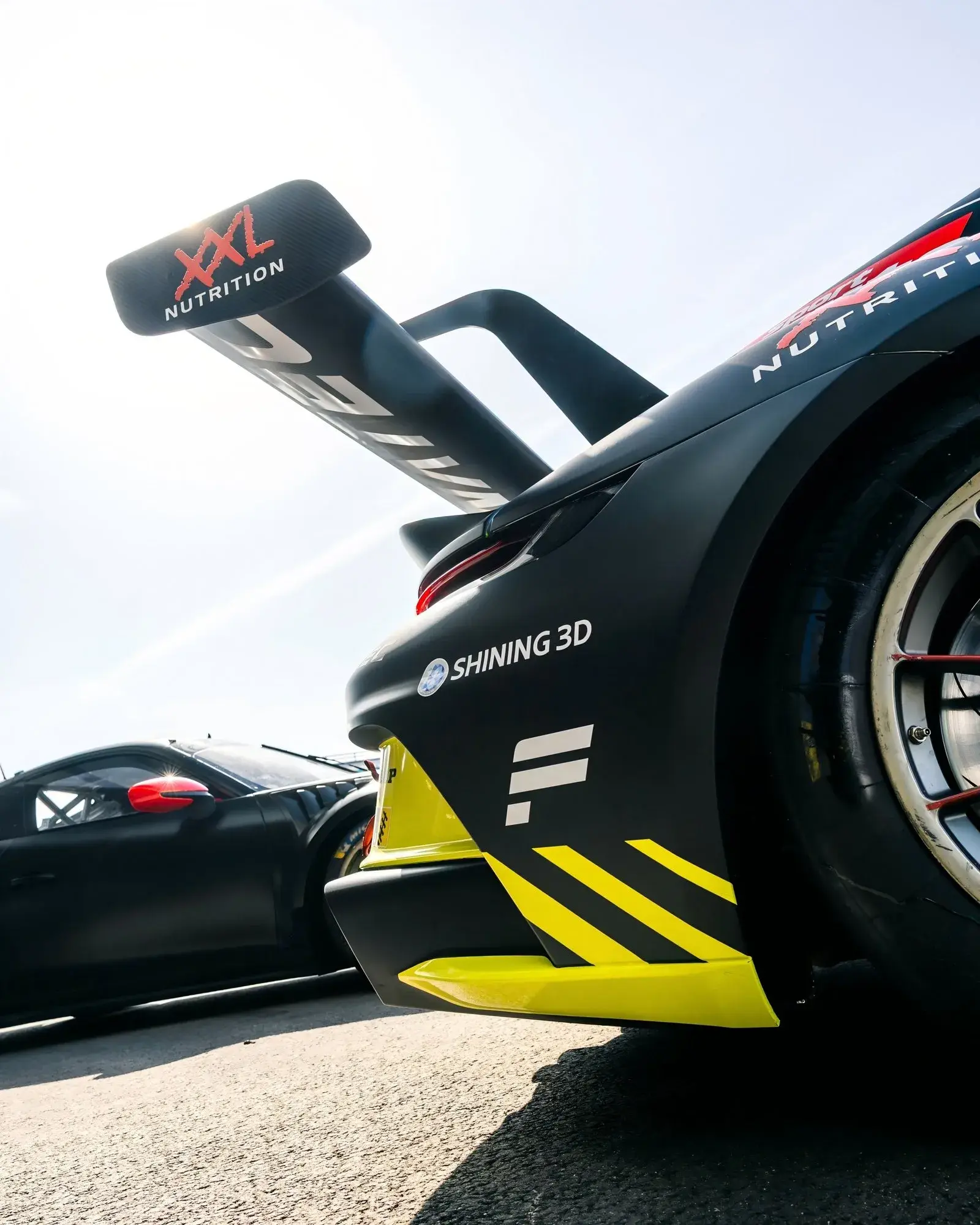 Voiture de course Black Falcon dans les stands avec la présence visuelle de SHINING 3D