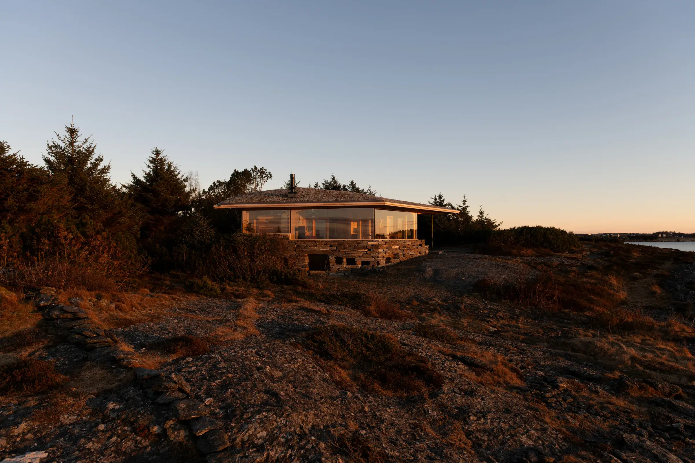 Cabin Sande, basse silhouette en bois et verre adossée à un promontoire rocheux au bord de l'Atlantique
