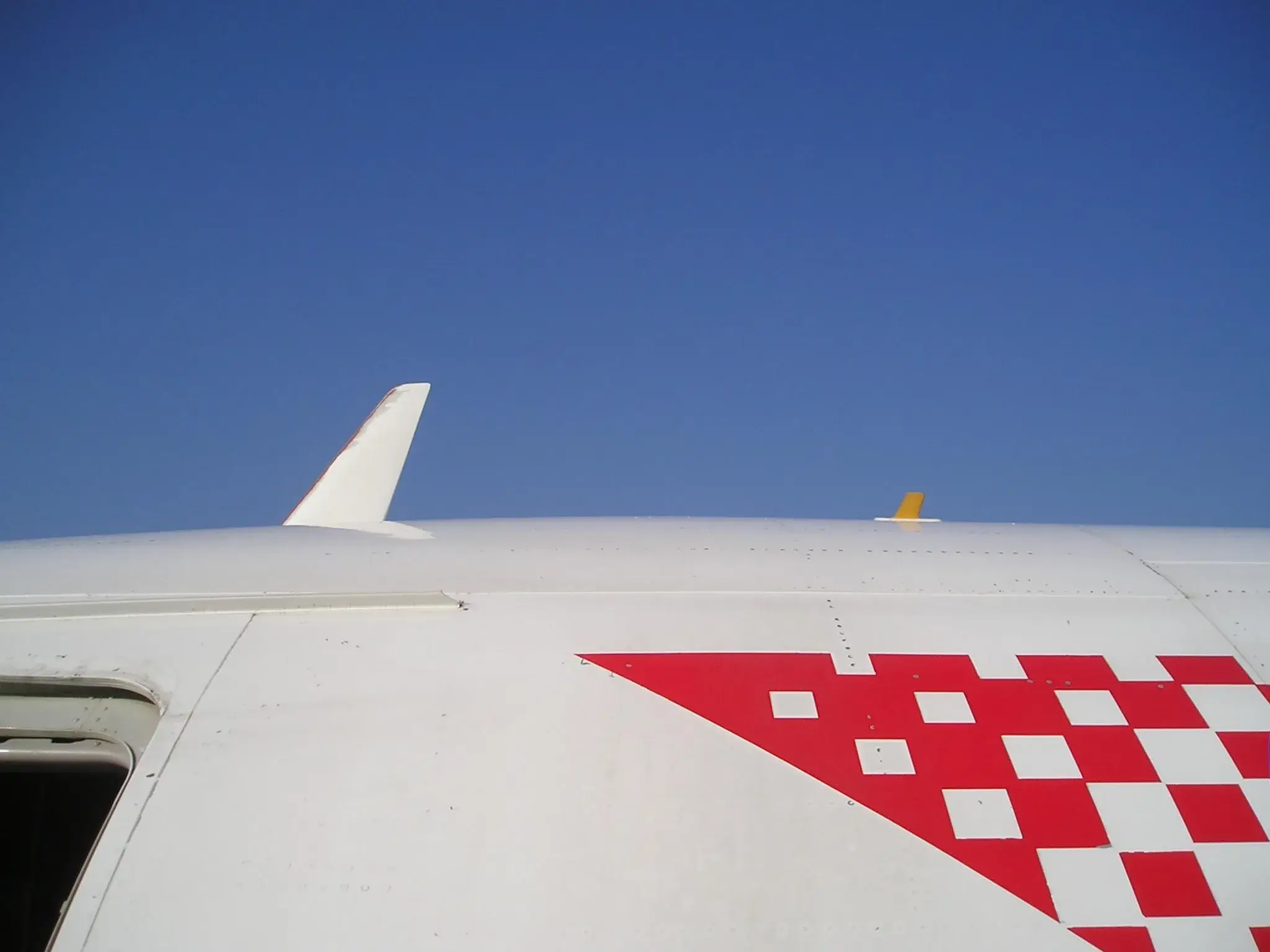 Deux antennes fuselage visibles sur le dessus d'un Airbus A319 : une lame blanche VHF et un petit aileron jaune