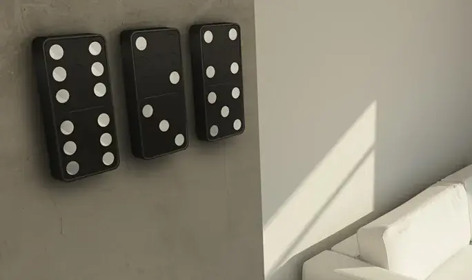 Trois grands dominos noirs à points blancs accrochés à un mur en béton