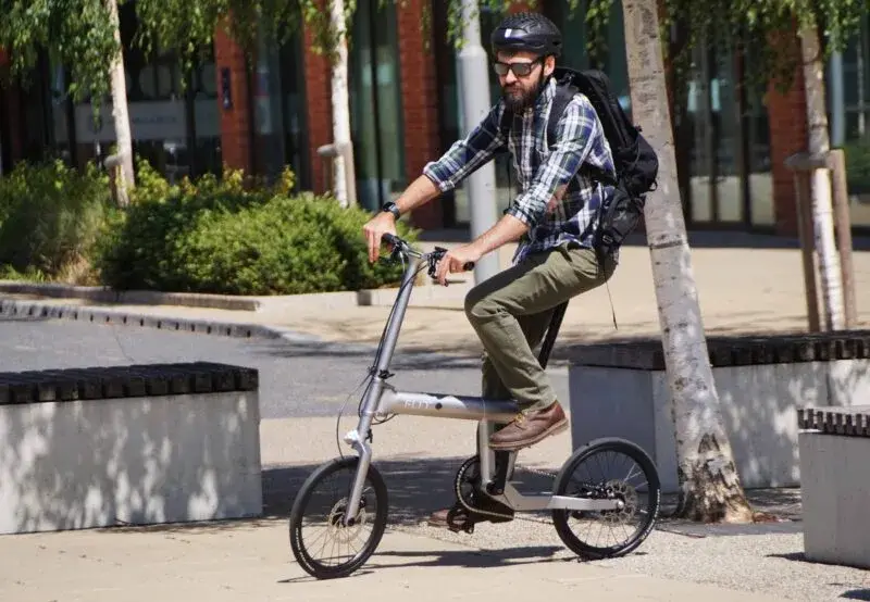 Un cycliste sur le vélo pliant électrique FLIT M2i dans un décor urbain