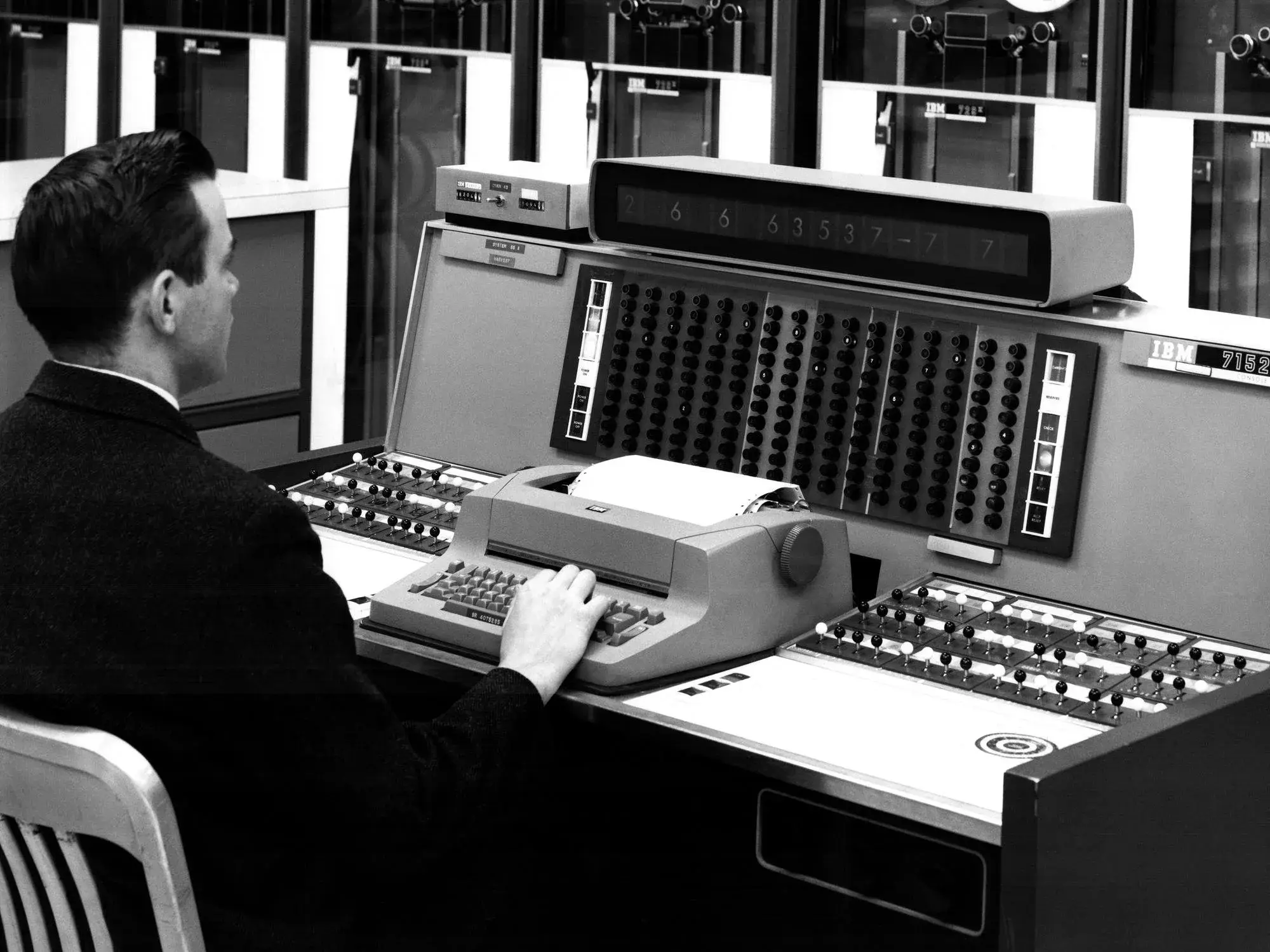 Un opérateur tape sur une machine à écrire Selectric détournée en console, équipement informatique en arrière-plan