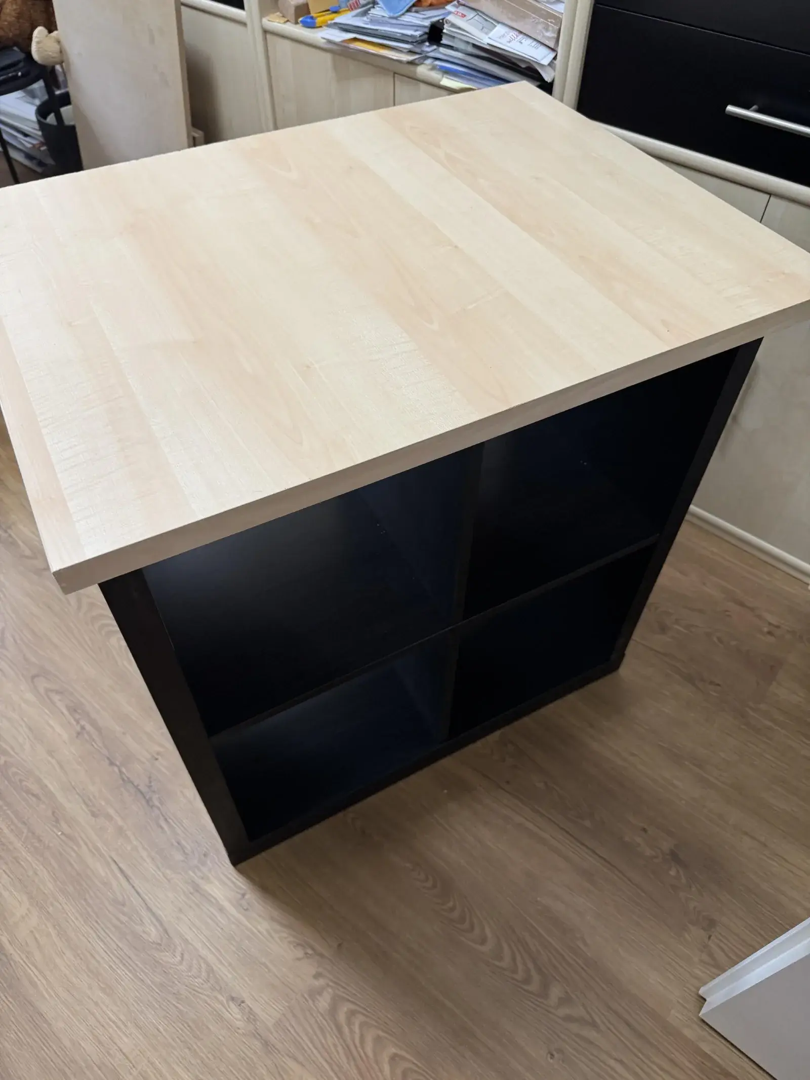 Établi de travail fait d'un caisson KALLAX noir surmonté d'un grand plateau de bureau, avec rangements