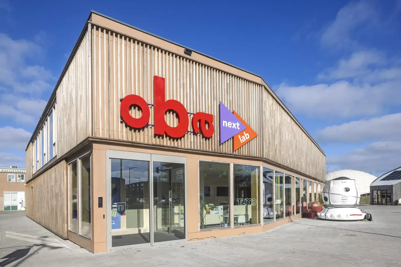 Façade de l'OBA Next Lab montrant le bardage bois et l'entrée du bâtiment temporaire