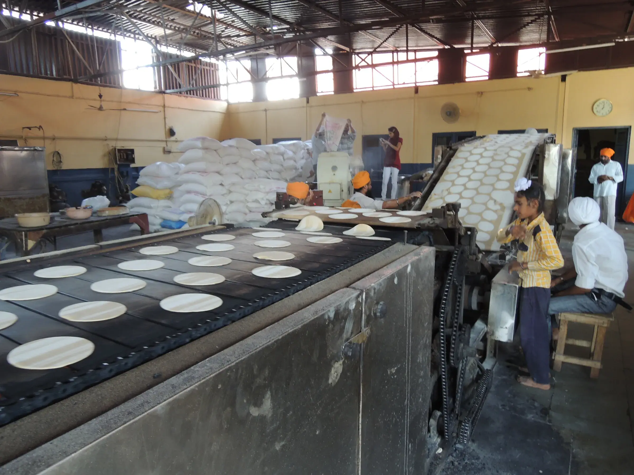 Machine automatique à chapatis en fonctionnement dans le langar du Temple d'Or d'Amritsar, avec des disques cuits alignés sur un tapis