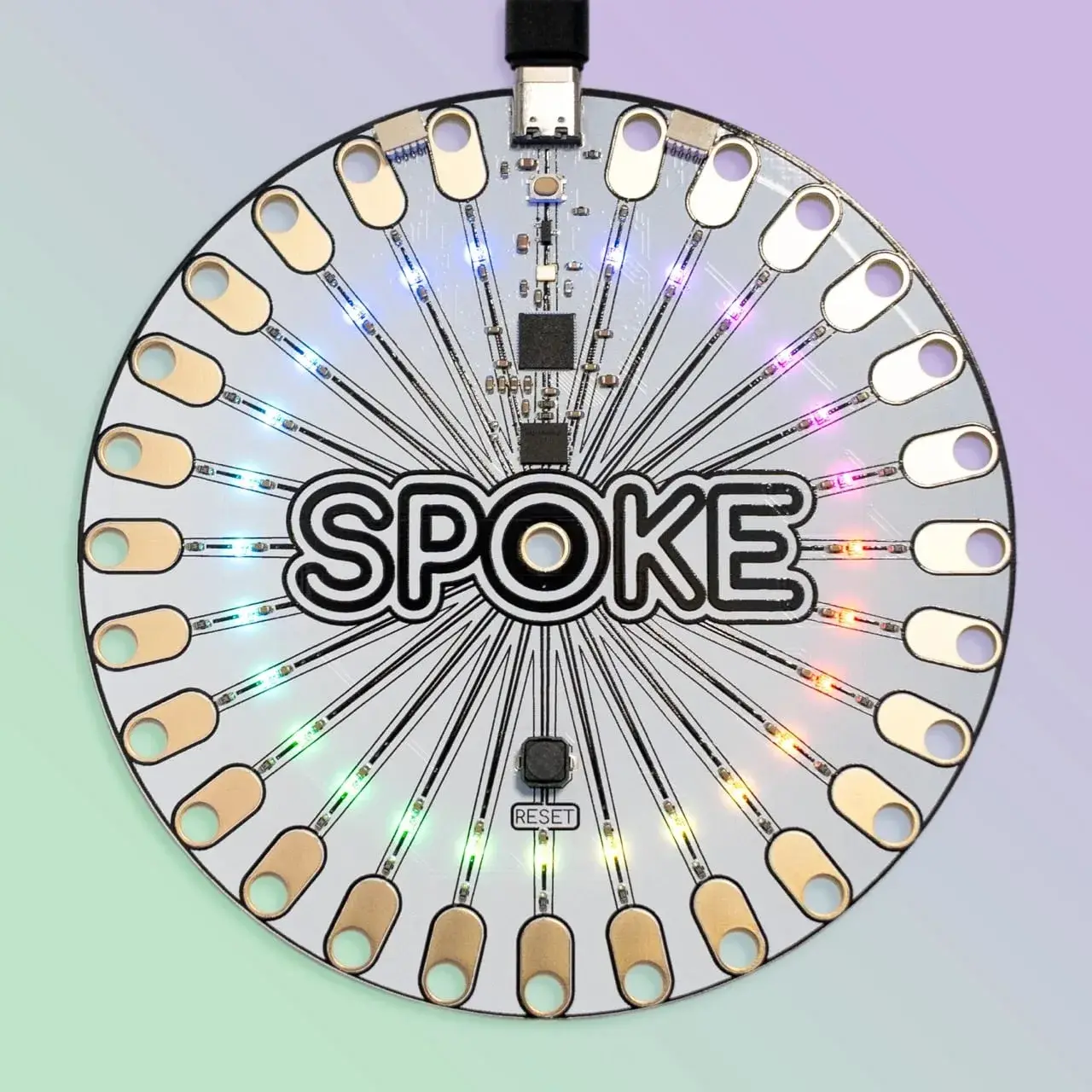 Le contrôleur SPOKE, un disque de circuit imprimé avec 27 pastilles de cuivre percées et des NeoPixels allumées