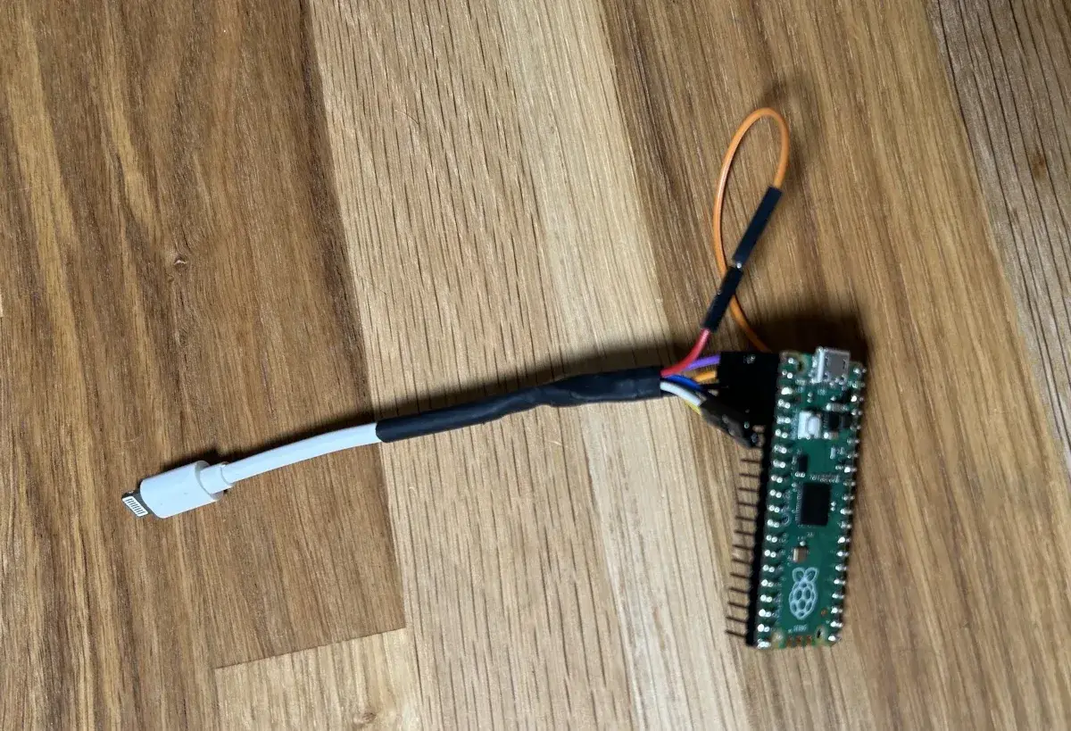 Un Raspberry Pi Pico 2 avec l'extrémité coupée d'un câble Lightning Apple blanc soudée sur ses broches