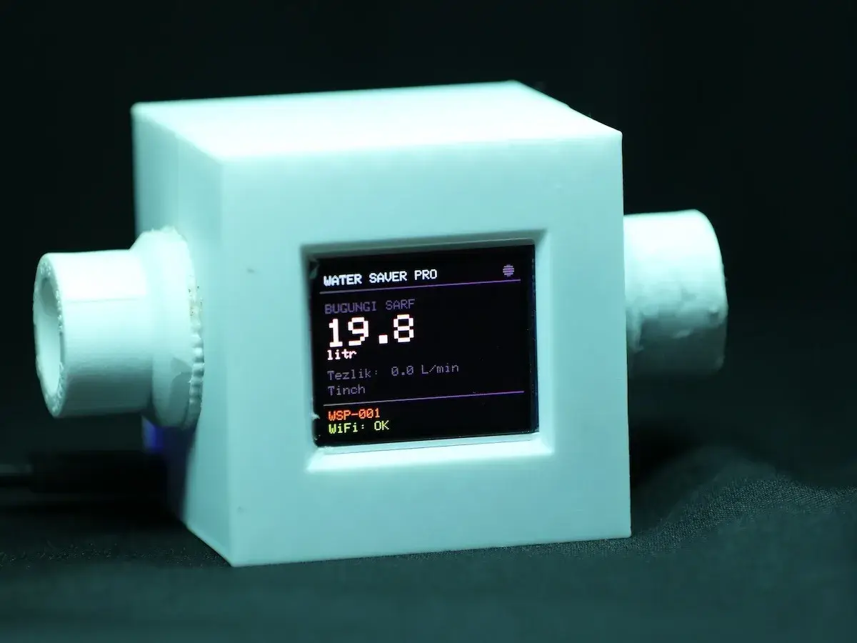 Prototype Water Saver Pro : boîtier blanc avec deux raccords de tuyau, écran affichant « Bugungi sarf 19.8 litr » et « WiFi : OK »
